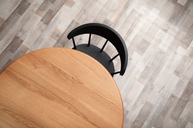 Photo of Round wooden table and black chair indoors, top view