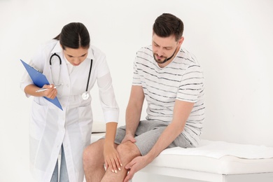 Doctor examining male patient with injured leg in clinic