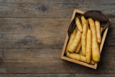 Photo of Raw white carrots in crate on wooden table, top view. Space for text