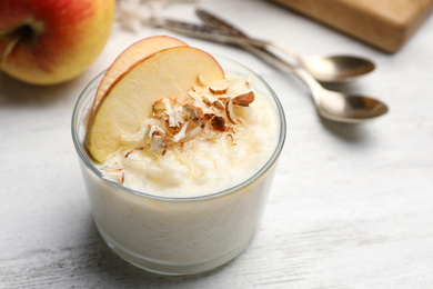 Delicious rice pudding with apple and almond on white wooden table, closeup