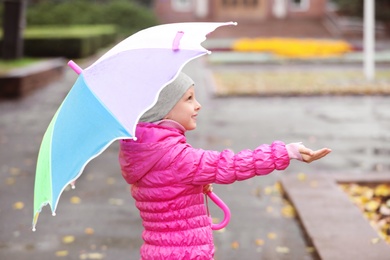 Photo of Little girl with umbrella in city on autumn rainy day