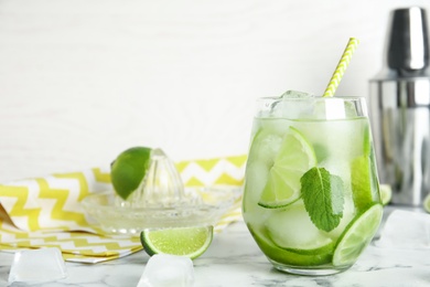 Photo of Delicious mojito and ingredients on white marble table. Space for text