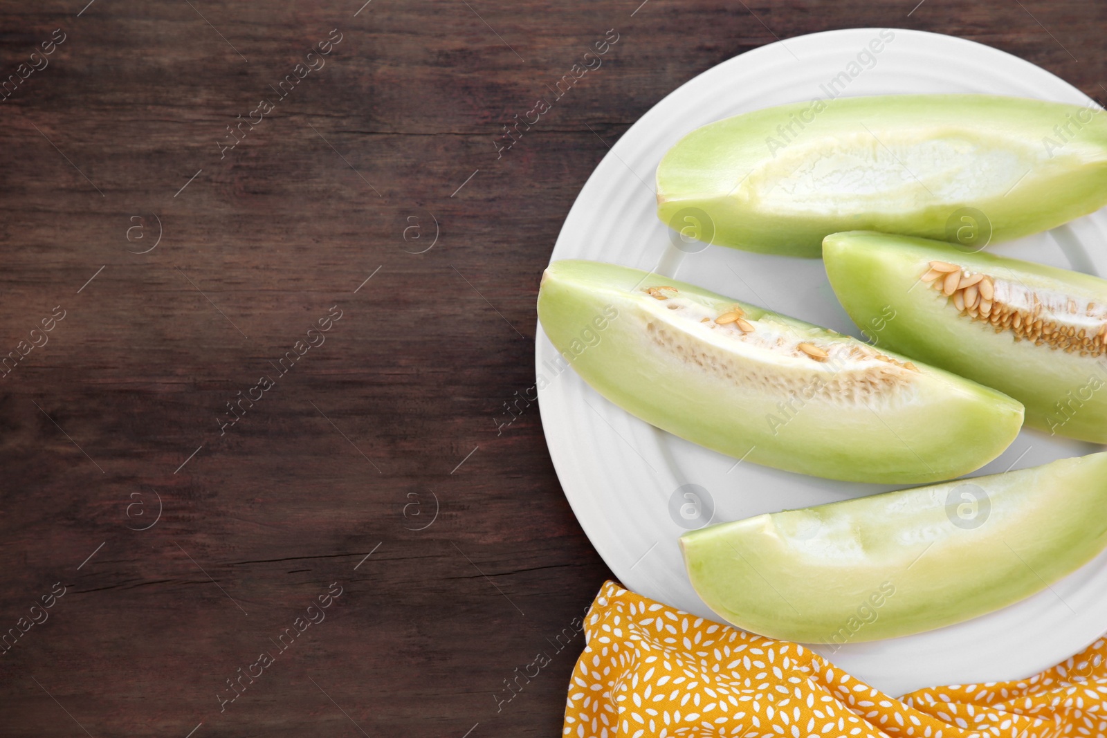 Photo of Cut tasty ripe melon on wooden table, flat lay. Space for text