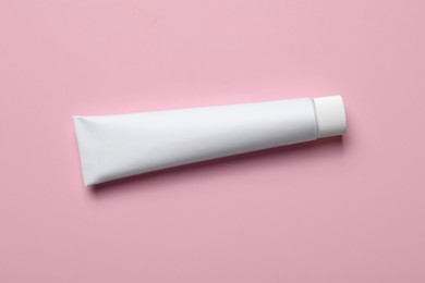 Photo of Blank tube of toothpaste on pink background, top view