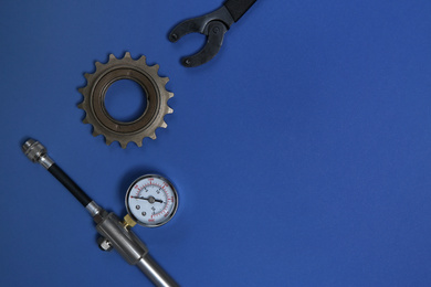 Manometer, sprocket and wrench on blue background, flat lay with space for text. Bicycle tools