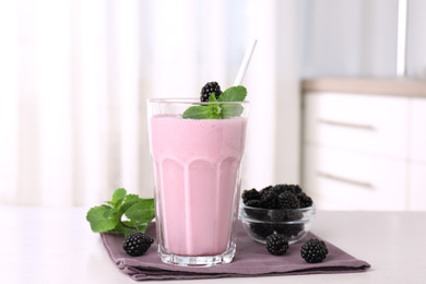 Photo of Tasty blackberry milk shake with fresh berries on white table