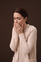 Photo of Woman coughing on brown background. Cold symptoms