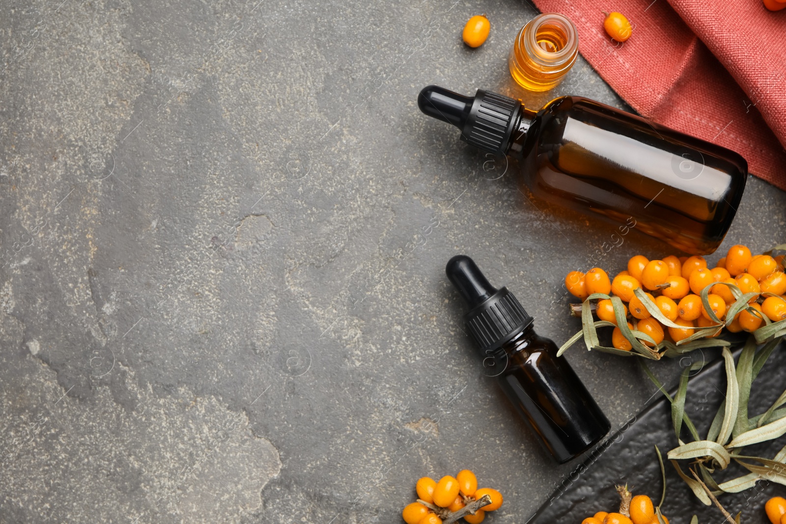 Photo of Flat lay composition with sea buckthorn oil on grey table. Space for text