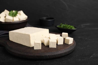 Photo of Delicious tofu and wooden board on black table