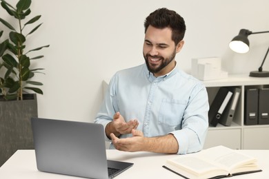 Photo of Young man having video chat via laptop at table indoors