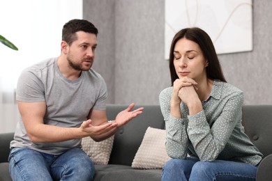 Photo of Offended wife ignoring her husband indoors. Relationship problems