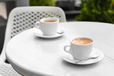 Photo of Ceramic cups of aromatic coffee with foam on table in morning