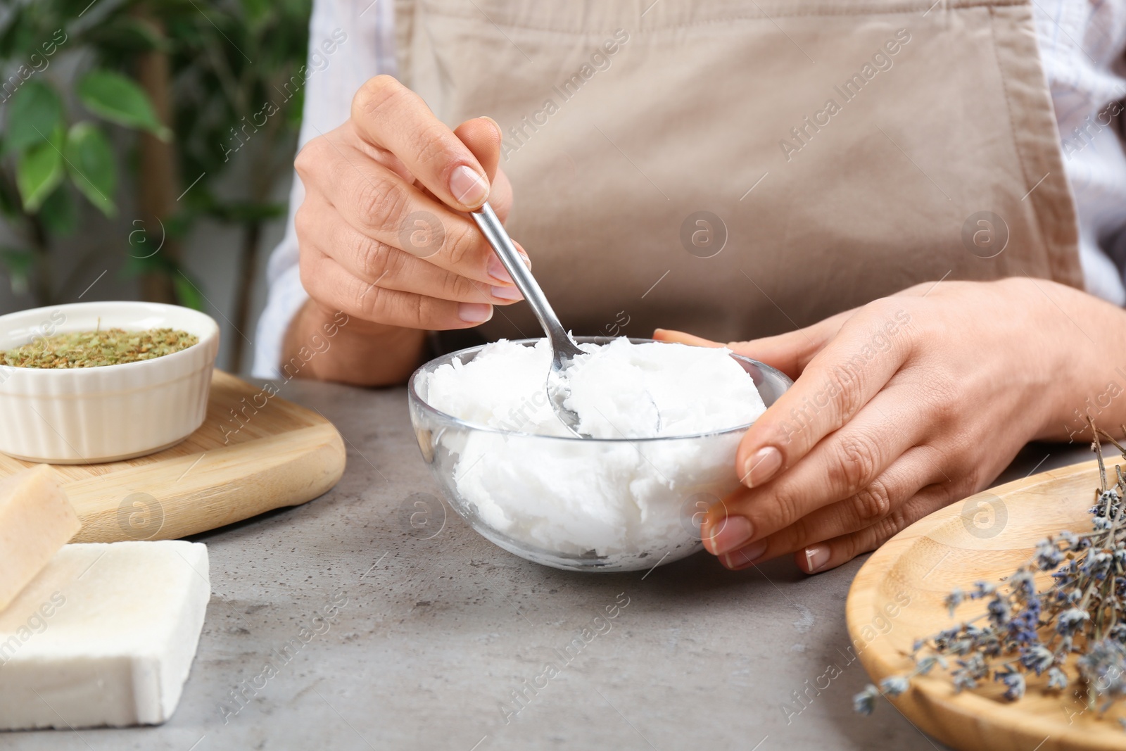 Photo of Woman making natural handmade soap at grey stone table, closeup