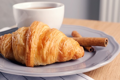 Photo of Plate with tasty croissant on table, closeup