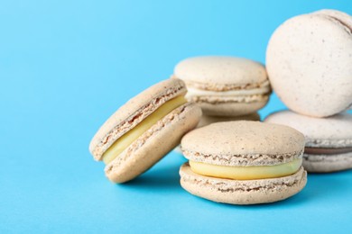 Photo of Pile of delicious colorful macarons on light blue background, closeup