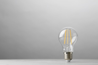 Photo of Vintage lamp bulb on light table against grey background. Space for text