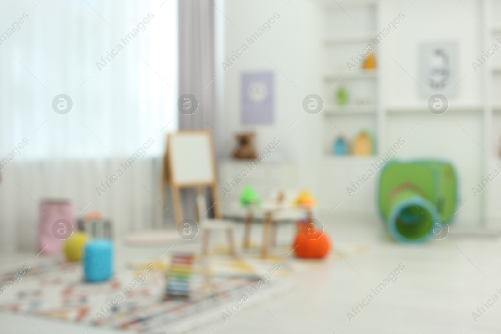 Photo of Blurred view of child`s playroom with different toys and furniture. Stylish kindergarten interior