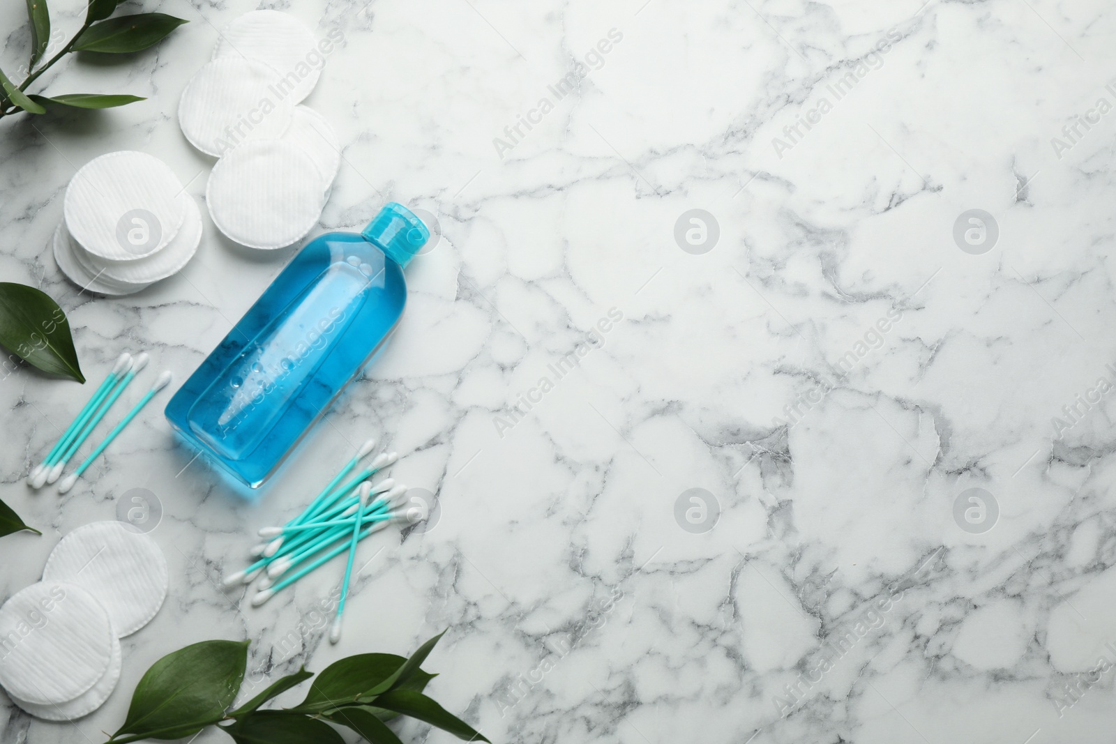 Photo of Cotton pads, swabs and makeup removal product on white marble table, flat lay. Space for text