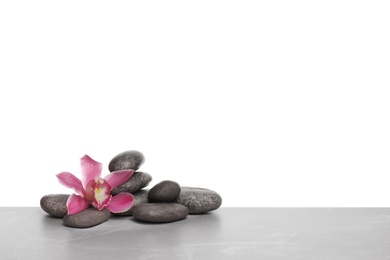 Photo of Orchid flower with spa stones on white background. Space for text