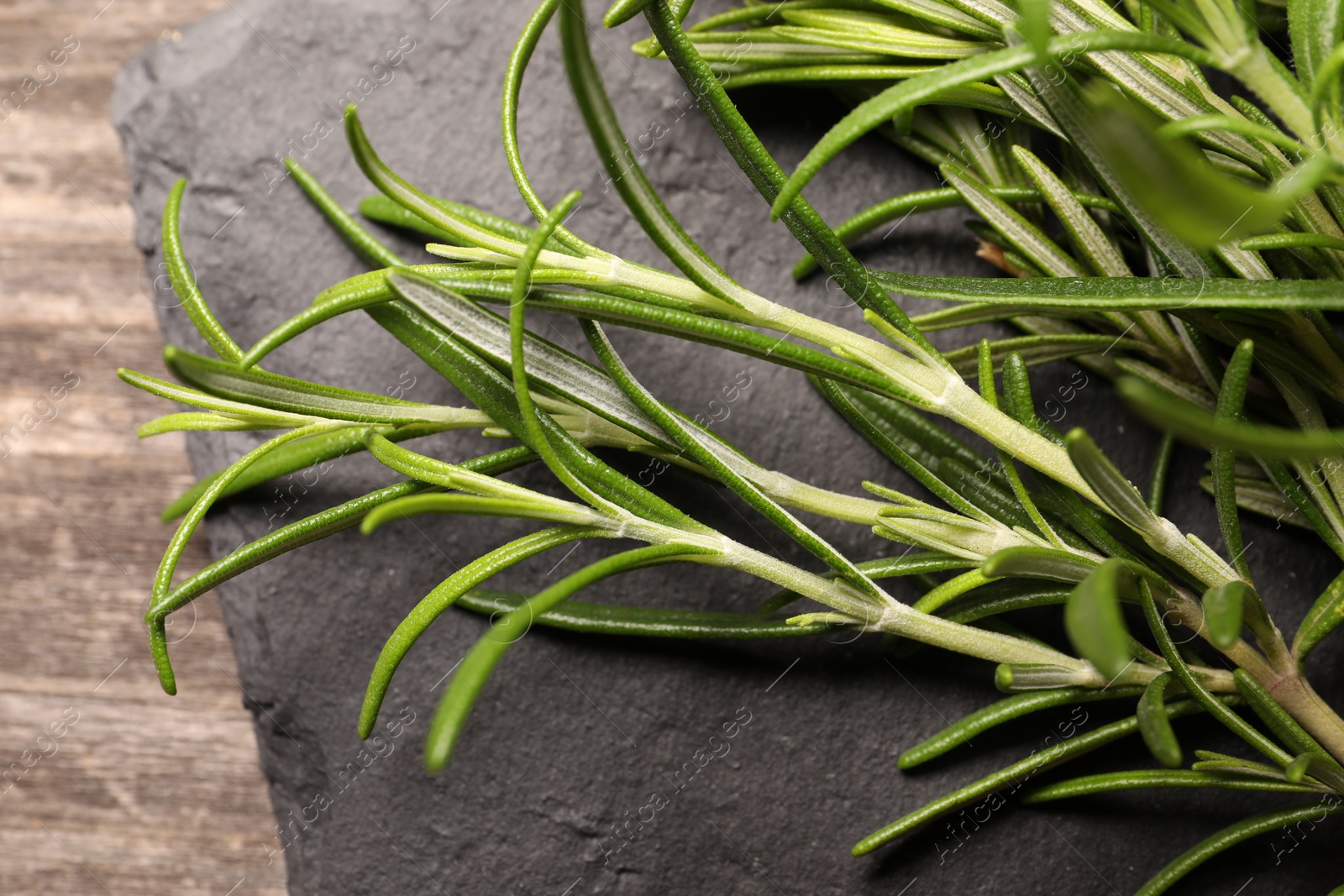 Photo of Fresh green rosemary with slate plate on table, closeup