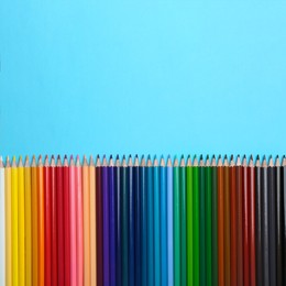 Image of Colorful pencils on light blue background, flat lay. Space for text