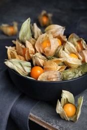 Photo of Ripe physalis fruits with dry husk on grey table, closeup
