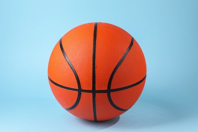 Photo of One orange basketball ball on light blue background