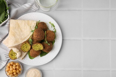 Photo of Delicious falafel balls served on white tiled table, flat lay. Space for text