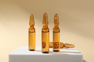 Photo of Glass ampoules with liquid on beige background