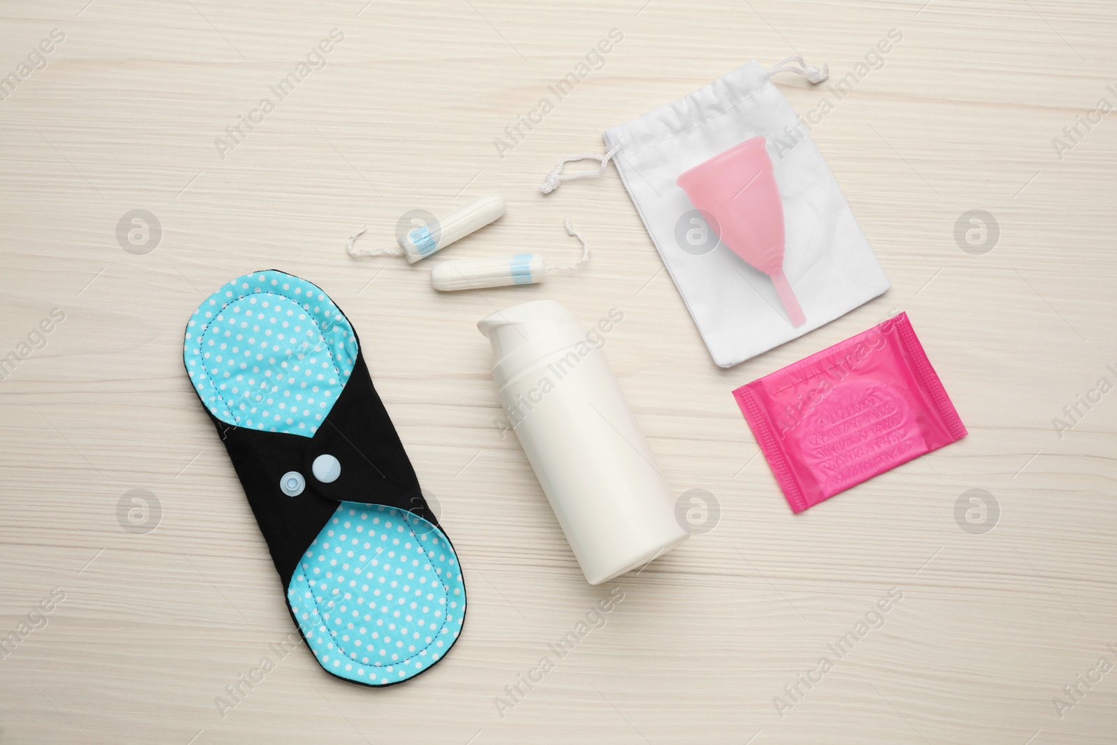 Photo of Cloth menstrual pad and other female hygiene products on white wooden table, flat lay