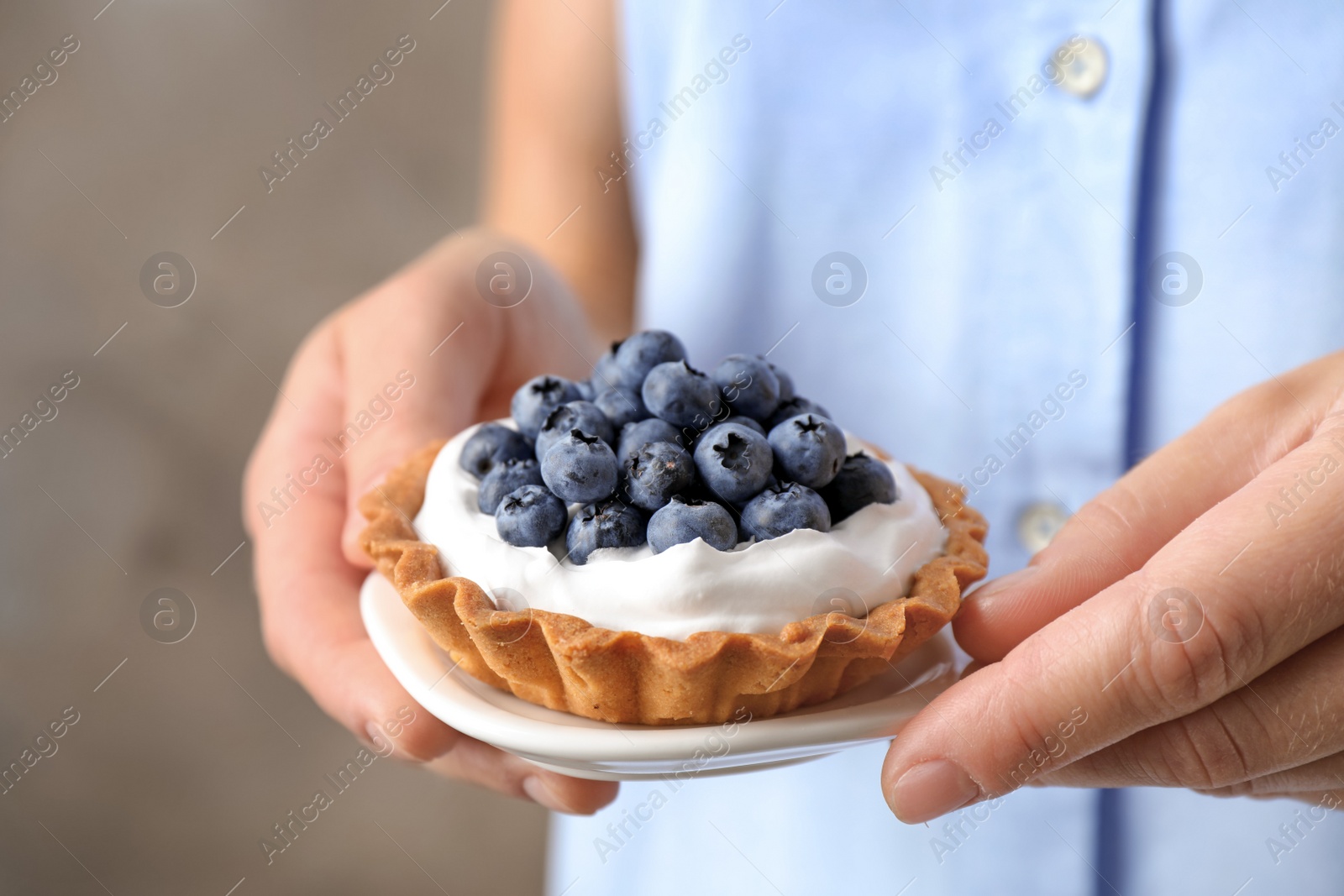 Photo of Woman holding plate with blueberry tart, closeup. Delicious pastries