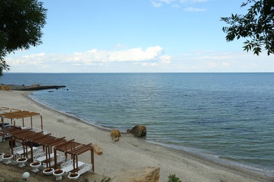 Picturesque view of sandy beach with cozy gazebos near sea