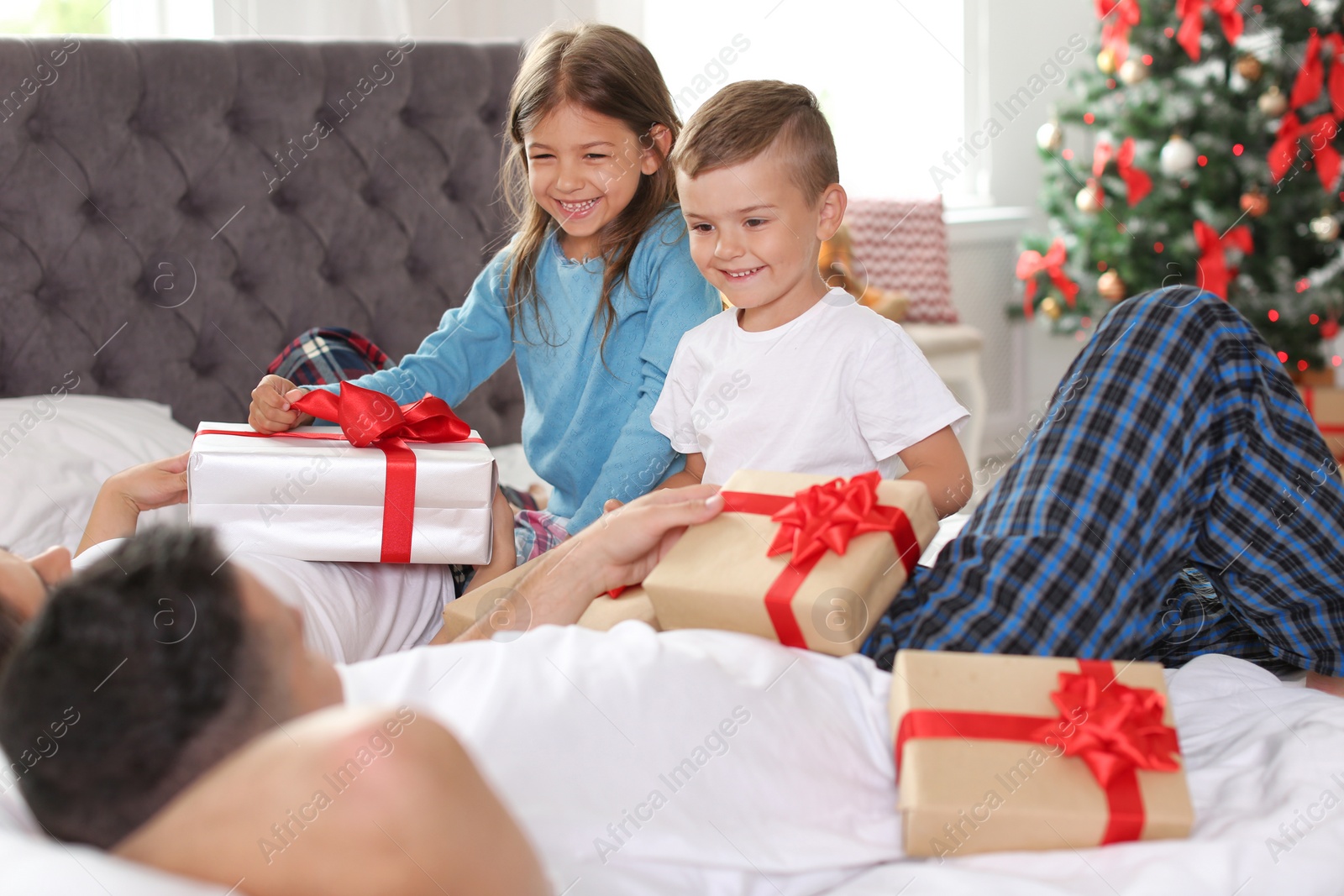 Photo of Happy parents and children with gifts celebrating Christmas at home