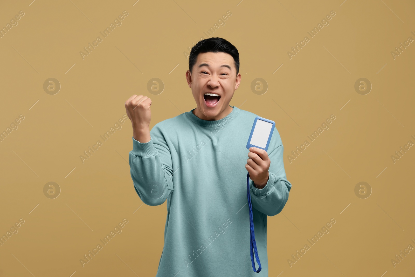 Photo of Emotional asian man with vip pass badge on beige background