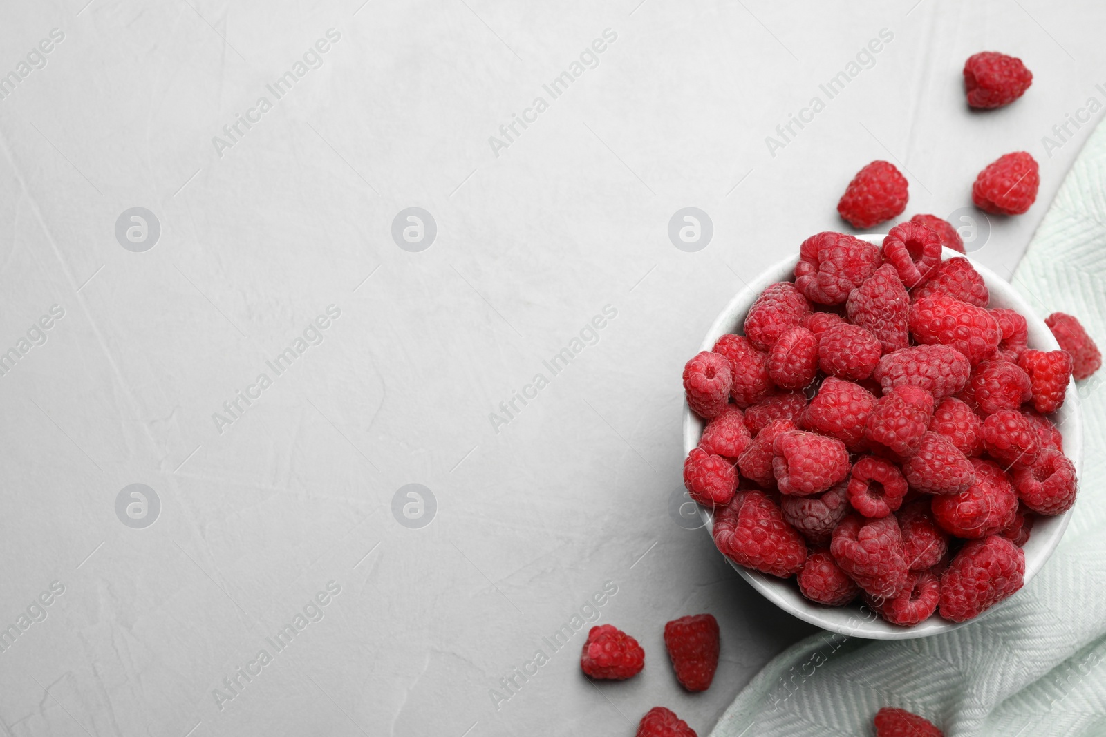 Photo of Bowl with delicious ripe raspberries on light background, top view. Space for text