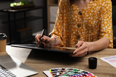 Professional designer with graphic tablet at wooden table, closeup