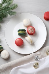 Photo of Different decorated Christmas macarons and festive decor on white wooden table, flat lay