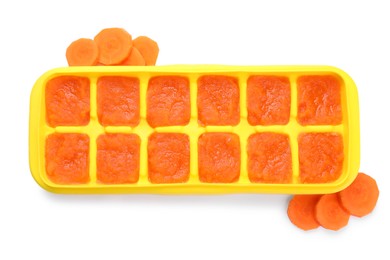 Photo of Carrot puree in ice cube tray isolated on white, top view. Ready for freezing