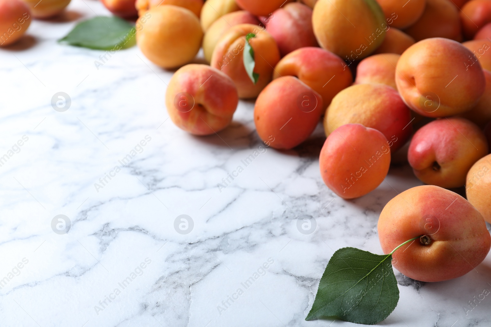 Photo of Many fresh ripe apricots on white marble table. Space for text