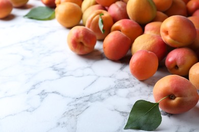 Photo of Many fresh ripe apricots on white marble table. Space for text