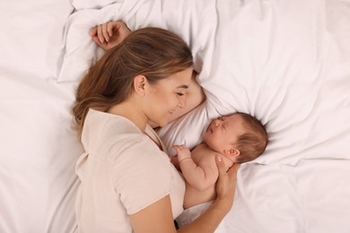 Mother and her cute newborn baby on bed, top view