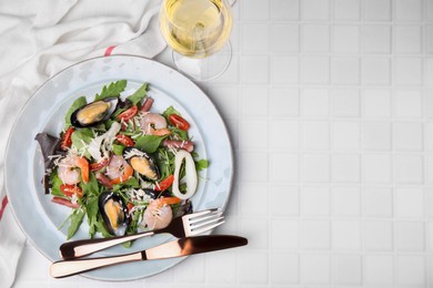 Plate of delicious salad with seafood on white tiled table, flat lay. Space for text