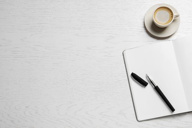 Photo of Open blank notebook, pen and coffee on white wooden table, flat lay. Space for text