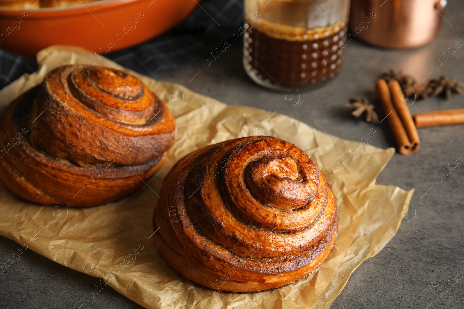 Photo of Parchment with freshly baked cinnamon rolls on table