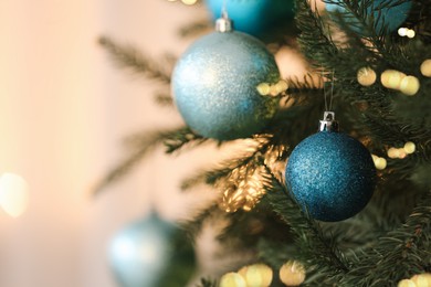 Photo of Christmas tree decorated with light blue festive balls on blurred background, closeup. Space for text