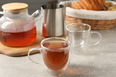 Photo of Aromatic tea in glass cup and teapot on light grey table