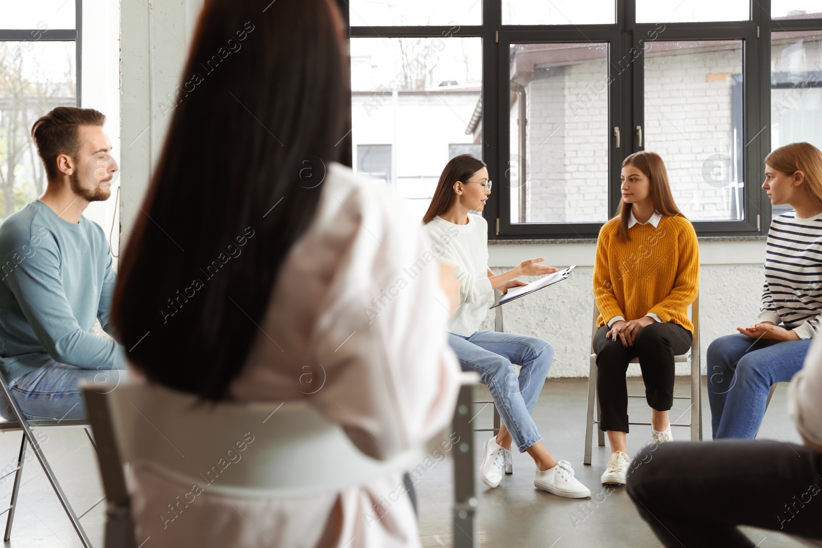 Photo of Psychotherapist working with patients in group therapy session indoors