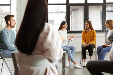 Photo of Psychotherapist working with patients in group therapy session indoors