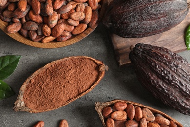 Photo of Flat lay composition with cocoa pods, beans and powder on grey table