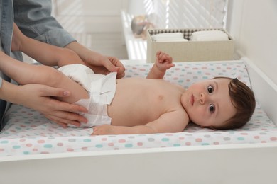 Mother changing baby's diaper on table at home, closeup